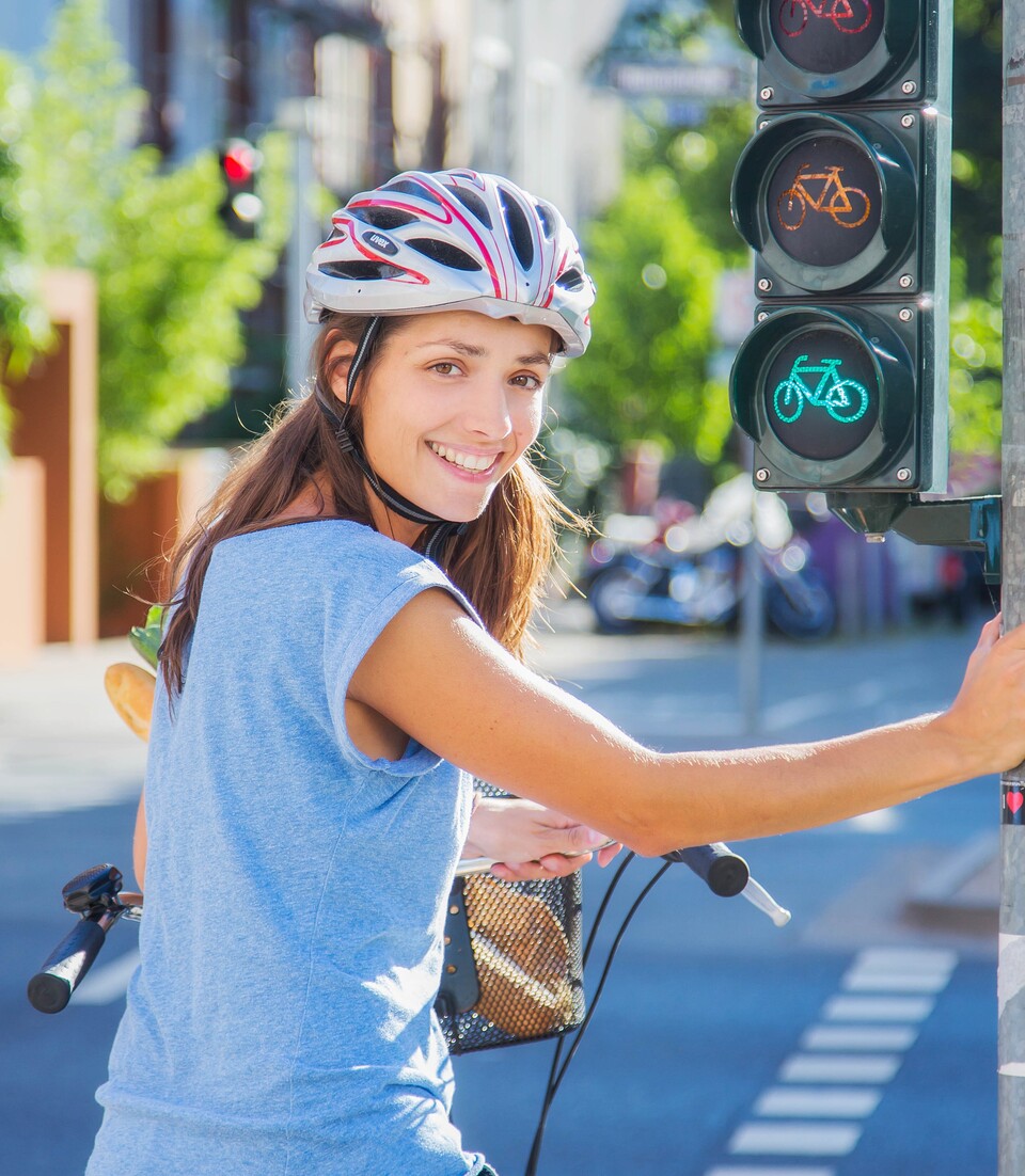 Frau mit Fahrrad-Helm an einer Fahrrad-Ampel | © STADTRADELN